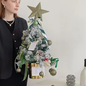 Mini flocked Christmas tree with gold pot, ornaments, pinecones and a star tree topper