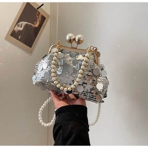 Detail of silver sequined evening bag with pearl top handle and golden clasp closure