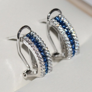 Elegant J-shaped silver earrings with three rows of pavé-set blue and white gemstones