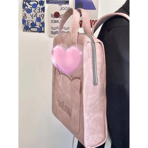 Detail of pink faux leather backpack featuring heart stitching and side carry style