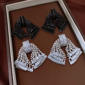 Close-up of black and silver bow tassel earrings with sparkling rhinestones in a tray