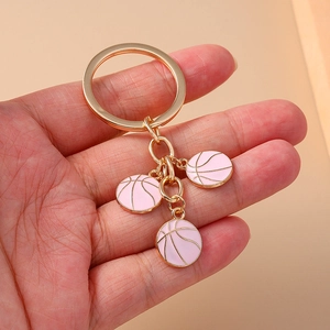 Detailed close-up of light pink enamel basketball charms with golden keychain rings