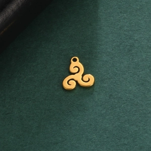 Macro shot of a golden triskele pendant with polished stainless steel finish on a dark texture