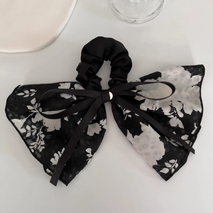 Close-up of floral print mesh bow and black satin scrunchie with gold buckle detail