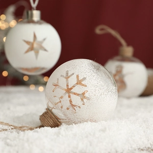 Clear glass Christmas ball with white snowflakes and stars on a rustic rope hanger