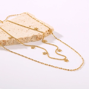 Gold-plated layered star pendant necklace on a decorative stone with a spherical chain