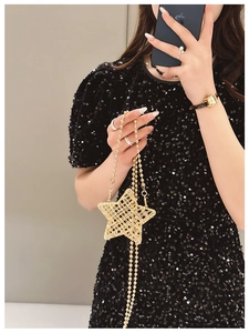 Detail of a shiny gold star-shaped metal mesh evening bag with long beaded chain strap