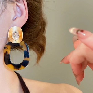 Close-up of tortoise shell resin earrings on model showing vintage aesthetic and size