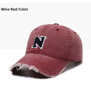 Detailed view of the distressed edges and embroidered N logo on a burgundy baseball cap