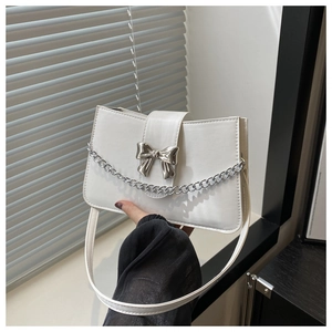 Close-up of white shoulder bag featuring a silver metal bow and chunky chain detail