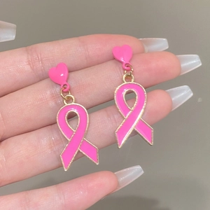 Detail von Ohrringen mit rosa Schleife, goldfarbenem Rahmen und Herz-Ohrstecker-Design