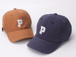 Close-up of embroidered letter P on brown and navy cotton baseball caps for kids
