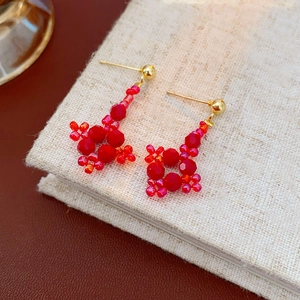 Macro detail of diamond-shaped floral beaded dangle earrings on a linen book cover