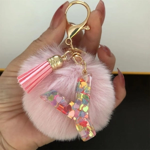 Detail of pink resin letter Y keychain with glitter hearts, plush pom pom and tassel