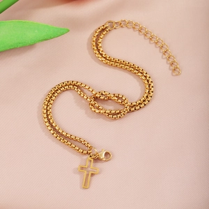 Detail of gold double-layer box chain bracelet with cross pendant and knot design
