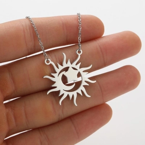 Detail of celestial sun pendant featuring moon and star cutouts on a fine chain link