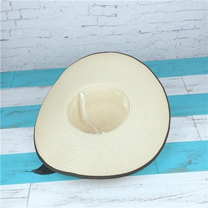 Detail of beige straw hat with dark brown trim and internal adjustable wind rope
