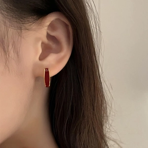 Elegant gold square hoop earrings with deep red glaze drip on minimalist model view