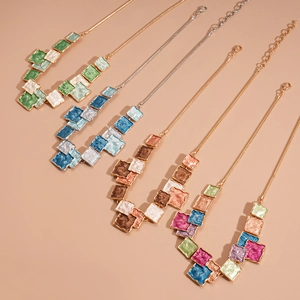 Macro view of geometric enamel square pendants on gold and silver snake chains