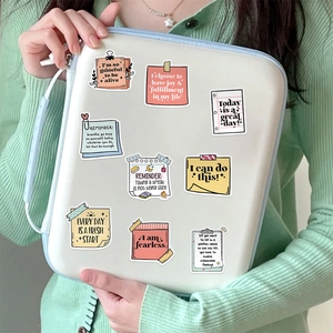 Close-up of colorful daily affirmation stickers applied to a white laptop cover case