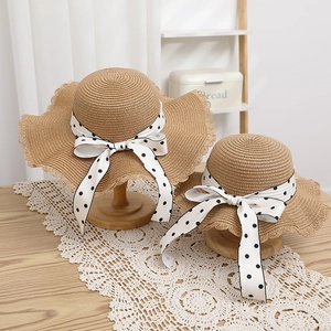 Detail of parent-child straw hat set with wave edges and polka dot silk ribbons