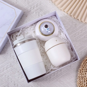 Close-up of a white coffee mug and astronaut humidifier in a gift box with white filler
