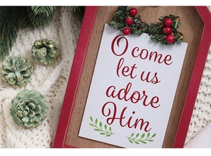 Detail of Christmas wooden door sign with red frame, red berries and green pine needles