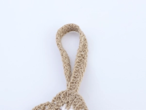 Detailed macro view of the beige hand-knitted halter strap texture and crochet craftmanship