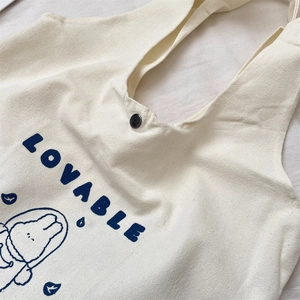Detail of a canvas tote bag showing a cute cartoon rabbit print and metal snap button
