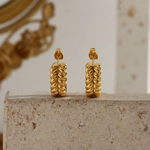 Detail of 18K gold plated C-shaped earrings with wheat pattern on stone base
