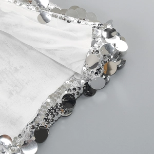 Close-up of silver sequins on white mesh fabric for sexy evening dress detail