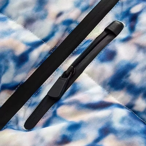 Detail view of waterproof zipper and marble print fabric on outdoor ski jacket