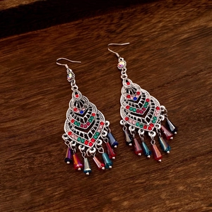 Close-up of bohemian silver drop earrings with colorful rhinestones on dark wood