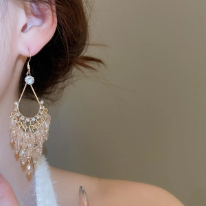 Detail of drop-shaped earrings with crystal tassels and gold frames on a model