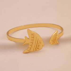Detail eines goldenen C-förmigen Titan-Armreifs mit zwei tropischen Fischmotiven