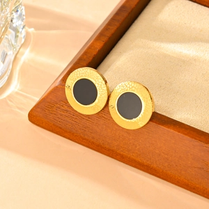 Macro shot of gold hammered metal earrings with black circular center inlay