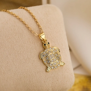 Chic 18k gold plated turtle pendant necklace with sparkling white zircons on beige stand