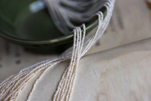 Macro shot of tiny white freshwater seed pearls strands for jewelry DIY on ceramic bowl