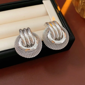 Detailed view of silver mesh hollow ball earrings with twisted knot in a jewelry box