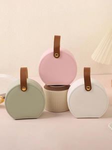 Close-up of small round jewelry bags with handles in pink, sage green, and beige PU leather