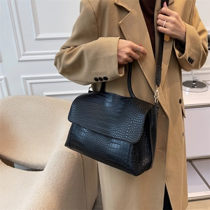 Fashionable black crocodile pattern tote bag with flap design shown in an indoor setting