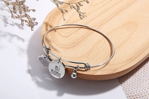 Détail d'un bracelet en acier argenté avec gravure mi mama et pendentif cœur de fête