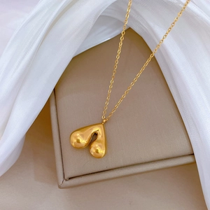 Elegant gold titanium heart pendant necklace displayed on jewelry box with soft fabric