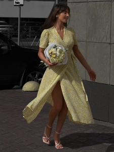 Detail of yellow floral wrap maxi dress with V-neckline and waist tie on the street