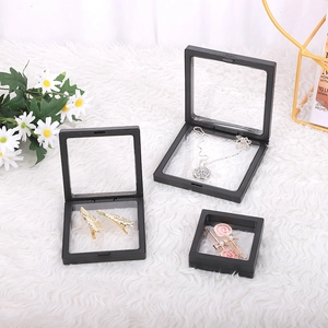 Three black PE film floating display boxes for jewelry on a white plush rug