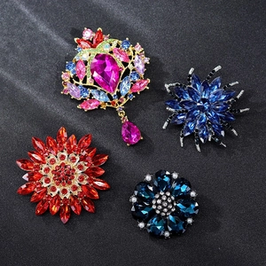 Macro shot of colorful crystal floral brooches with pearl accents on a dark grey background