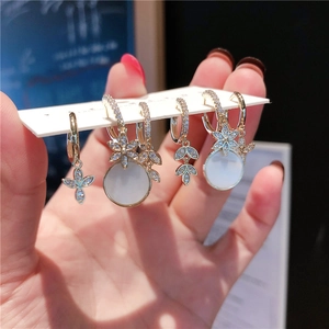 Detail of 6-piece gold earring set with cat-eye stone, floral designs, and zircon accents