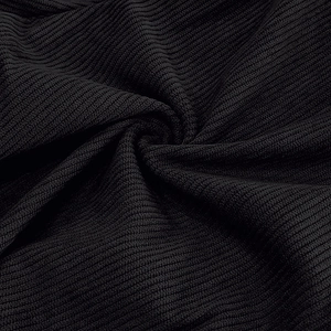 Detailed macro view of black corduroy fabric texture and ribbed knit craftsmanship on trousers