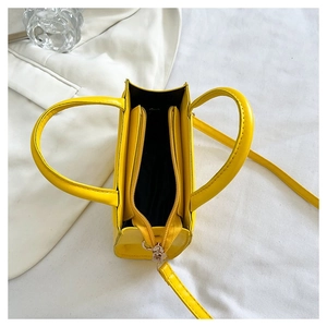 Vue de dessus d'un petit sac carré jaune avec fermeture éclair et bandoulière