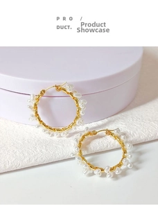 Detailed macro view of large gold hoop earrings wrapped with white baroque pearls